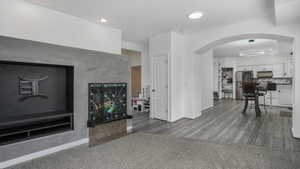 Living room with baseboards, arched walkways, light wood finished floors, and recessed lighting