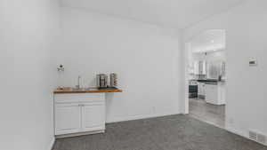 Interior space featuring a sink, arched walkways, carpet, gas range, and visible vents