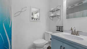 Bathroom featuring vanity, curtained shower, and toilet