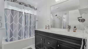 Bathroom featuring a sink, double vanity, and shower / tub combo