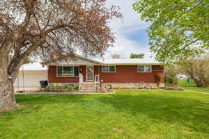 Ranch-style home with brick siding, a garage, a front lawn, and a chimney
