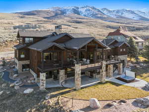 Back of property featuring a patio, a deck with mountain view, stairs, and stone siding