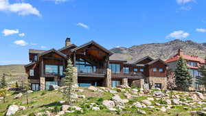 Back of property featuring stone siding, a mountain view, and a chimney
