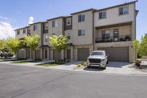 Townhome / multi-family property featuring concrete driveway, stone siding, and a garage
