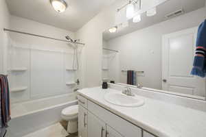 Bathroom featuring visible vents, bathtub / shower combination, vanity, tile patterned floors, and toilet