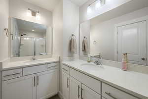 Bathroom featuring a sink, a shower stall, and two vanities