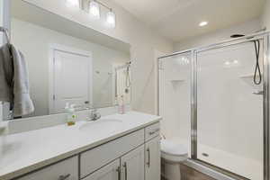 Bathroom with vanity, a shower stall, and toilet
