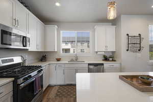 Kitchen with a sink, appliances with stainless steel finishes, a healthy amount of sunlight, and light countertops