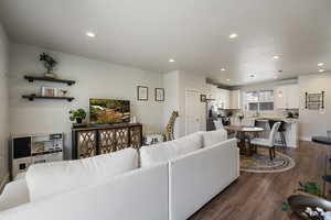 Living room featuring baseboards, recessed lighting, and dark wood-style floors