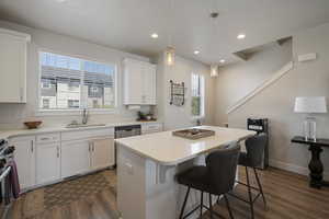 Kitchen featuring dark wood-type flooring, a sink, a breakfast bar area, and a healthy amount of sunlight