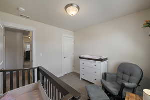 Carpeted bedroom featuring baseboards and visible vents