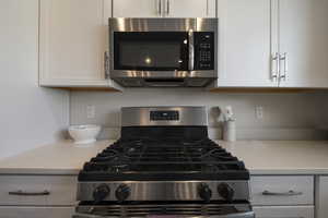 Kitchen featuring light stone counters, white cabinets, and stainless steel appliances