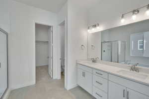 Bathroom featuring double vanity, a sink, a stall shower, and tile patterned flooring