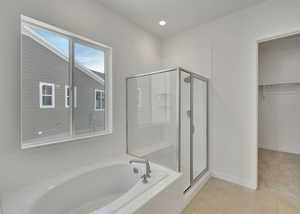 Full bath with tile patterned flooring, baseboards, a spacious closet, a garden tub, and a stall shower