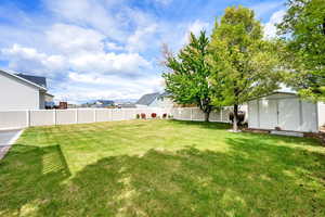 View of yard with a fenced backyard and a storage shed