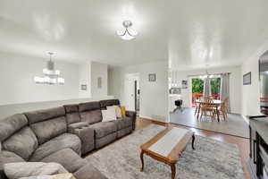 Living area with baseboards, a chandelier, and wood finished floors