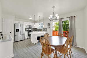 Dining space featuring light wood-type tile, baseboards, and a chandelier