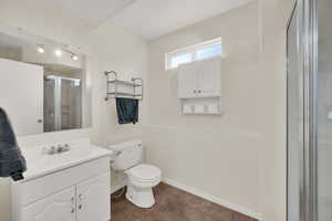 Full bath with vanity, toilet, tile patterned floors, baseboards, and a shower stall