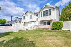 Split foyer home with a front yard, a garage, brick siding, fence, and concrete driveway
