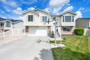Bi-level home with fence, an attached garage, concrete driveway, and a front yard