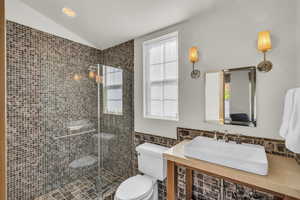 Bathroom with a sink, tile walls, plenty of natural light, and toilet