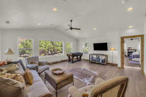 Living area featuring baseboards, a ceiling fan, light wood finished floors, and lofted ceiling
