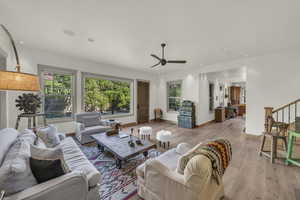 Living area featuring light wood-style flooring, a ceiling fan, baseboards, recessed lighting, and stairway