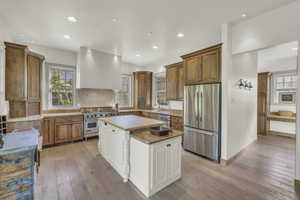 Kitchen with a sink, ventilation hood, brown cabinets, and stainless steel appliances