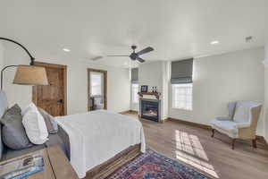 Bedroom with recessed lighting, visible vents, a glass covered fireplace, and light wood finished floors
