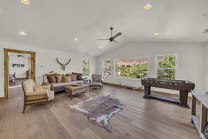 Living area featuring plenty of natural light, light wood-style flooring, ceiling fan, and lofted ceiling