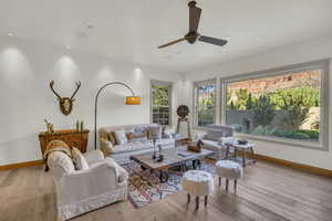Living room featuring a ceiling fan, baseboards, and light wood-style flooring