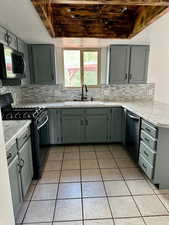 Kitchen with a sink, appliances with stainless steel finishes, backsplash, and light tile patterned flooring