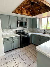 Kitchen featuring a sink, decorative backsplash, stainless steel appliances, and light tile patterned flooring