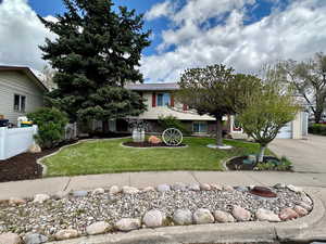 Obstructed view of property with fence, a garage, driveway, and a front yard