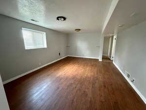 Unfurnished room with visible vents, baseboards, and dark wood-style floors