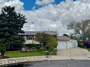 View of front of property featuring concrete driveway, an attached garage, metal roof, and a front yard