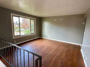 Interior space with baseboards, a textured ceiling, and wood finished floors