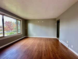 Empty room with baseboards, visible vents, and wood finished floors