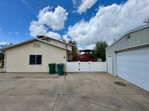 View of side of property with a garage, a gate, driveway, and fence