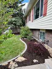 View of property exterior with fence, a yard, and brick siding