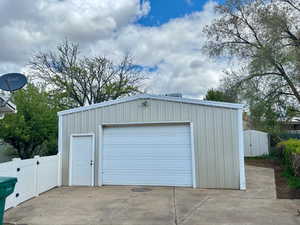 Detached garage featuring fence and concrete driveway