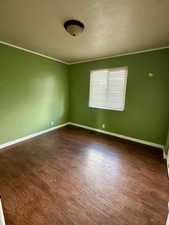 Spare room with baseboards, a textured ceiling, and dark wood-style floors