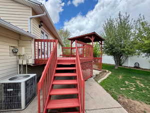 Deck featuring a yard, fence, cooling unit, and stairs