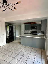 Kitchen with light countertops, tasteful backsplash, a sink, light tile patterned floors, and black appliances