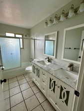 Bathroom with double vanity, a sink, combined bath / shower with glass door, and tile patterned floors