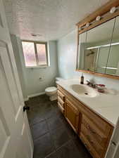 Full bathroom featuring vanity, a shower stall, a textured ceiling, and visible vents