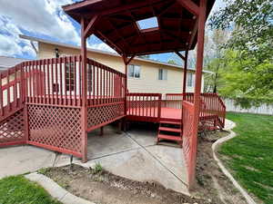 Wooden terrace with a lawn, a patio, and a gazebo