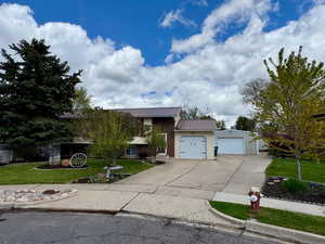 View of front facade featuring a garage, a front lawn, driveway, and metal roof
