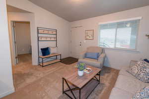 Carpeted living area featuring baseboards and vaulted ceiling