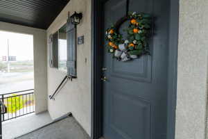 Doorway to property featuring stucco siding and covered porch